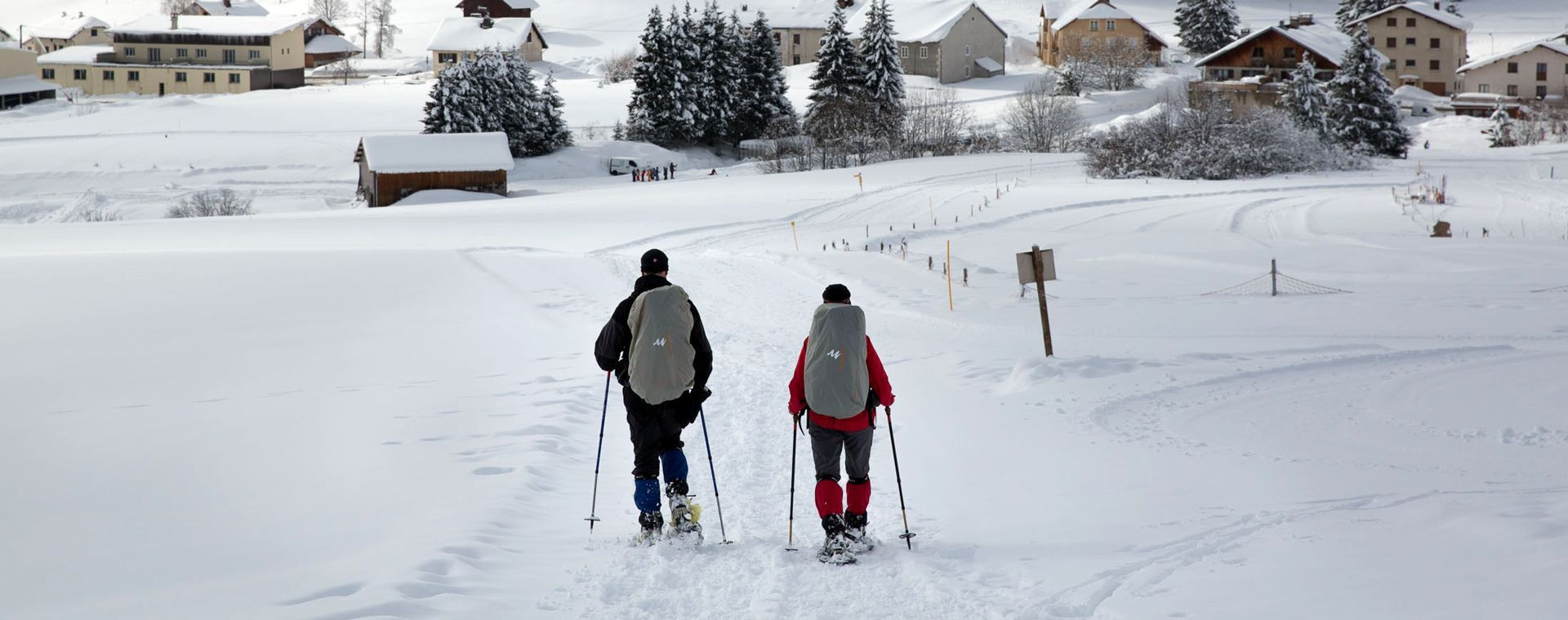 Raquetteurs vers un village enneigé en hiver - Jura - France